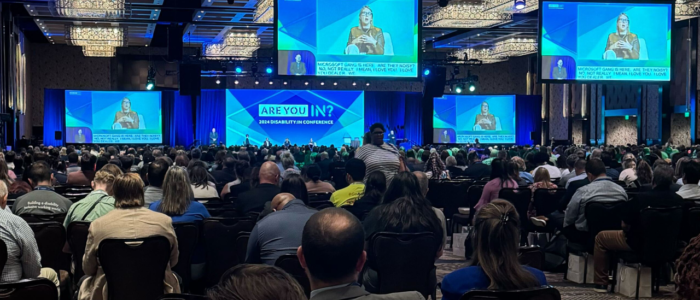 Thousands of accessibility advocates seated in a packed conference area at the Cosmopolitan in Las Vegas, Nevada. The group looks upon opening remarks.